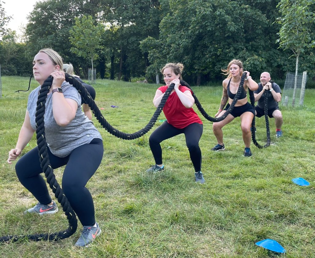 Battle Fit Bootcamp attendees exercising together with a battle rope.