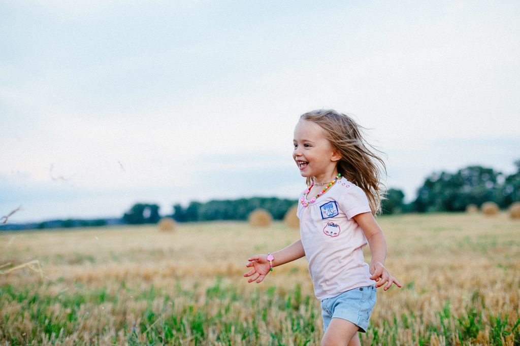 Young girl walking care free through a field with a beautiful smile