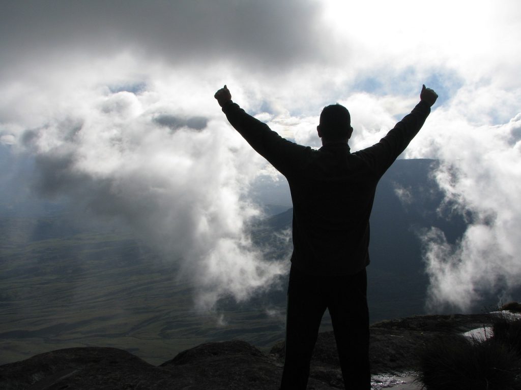 Man celebrating achievement at the summit of a mountain