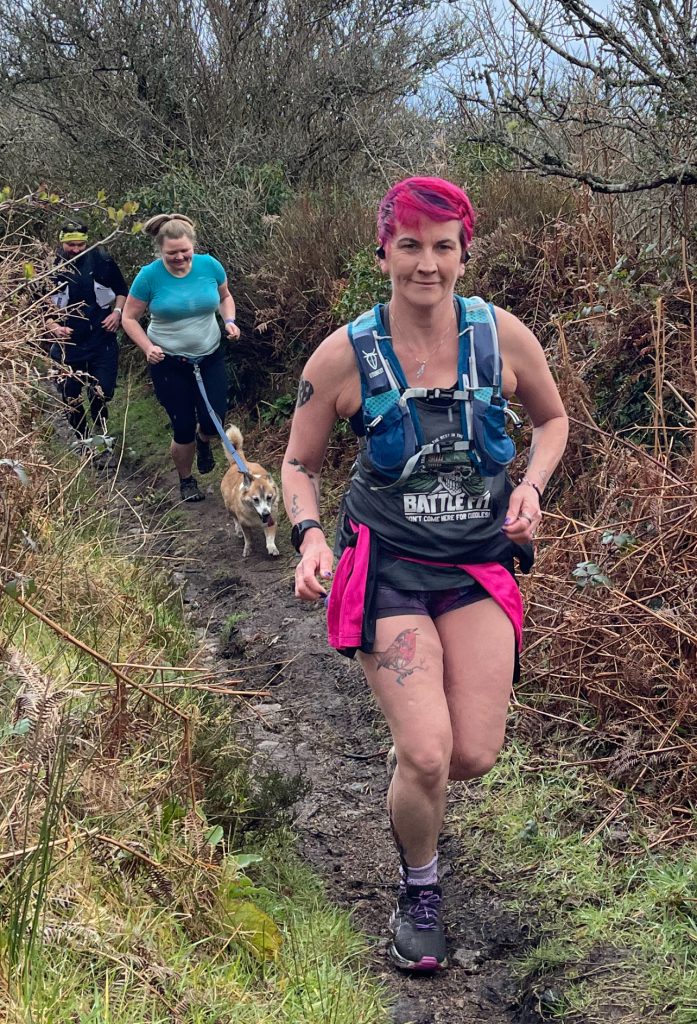 A female runner running through the muddy trails on Battle Fit's Run N Trail adventures.